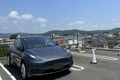 屋上のテスラ充電区画に停めたグレーのテスラ・モデルYと奥に並ぶウォールコネクター