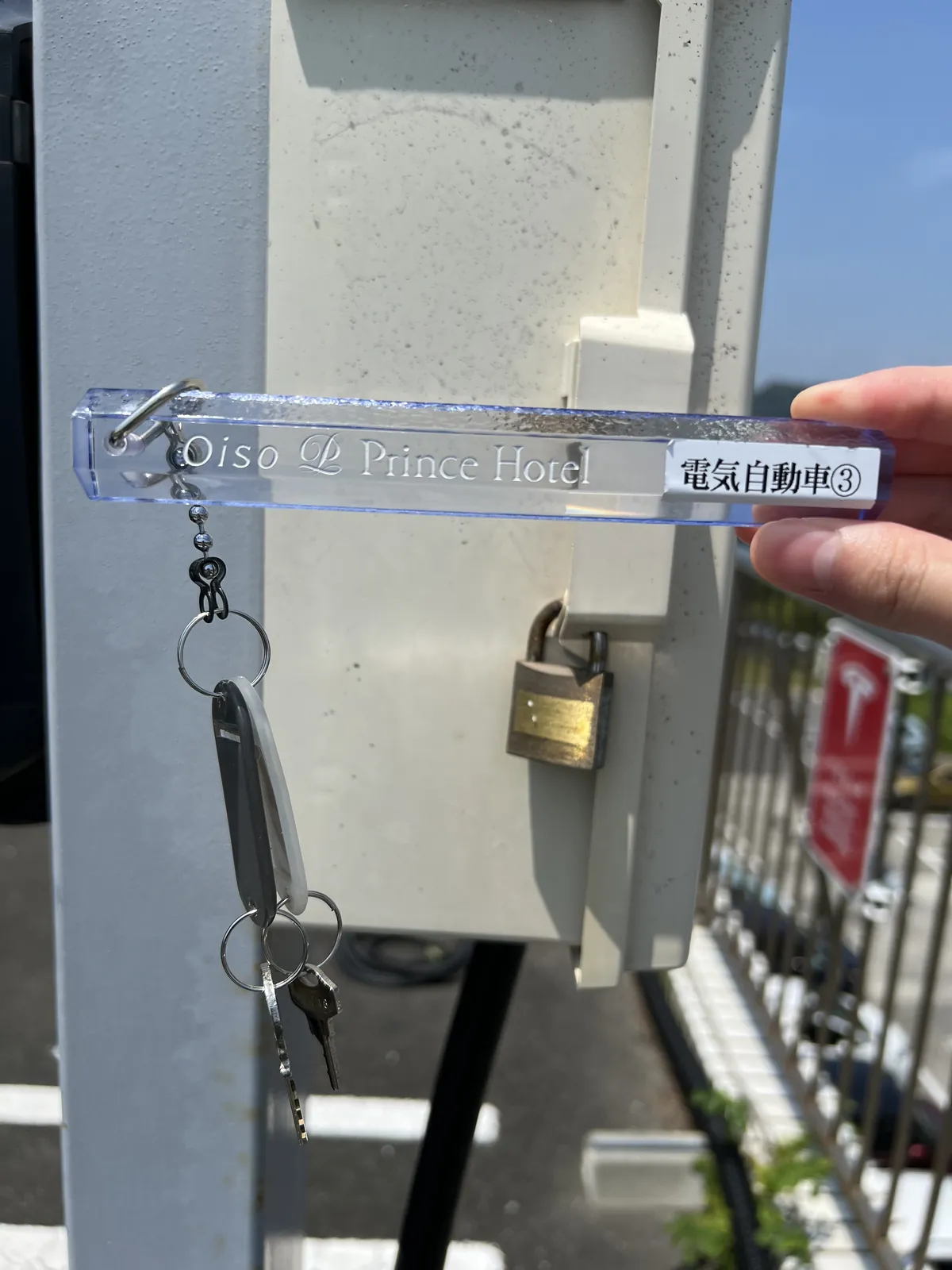 「電気自動車③ Oiso Prince Hotel」と刻印されたアクリル製キーホルダーと南京錠の鍵